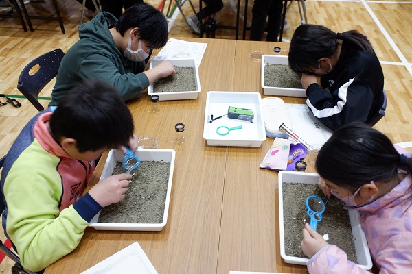 川原の土砂の中からプラスチックだと思うものを探す様子