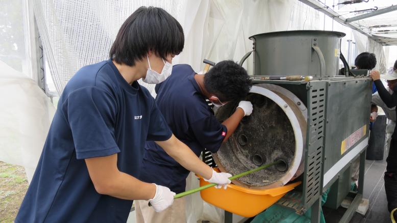 暖房機を掃除する学生(2)